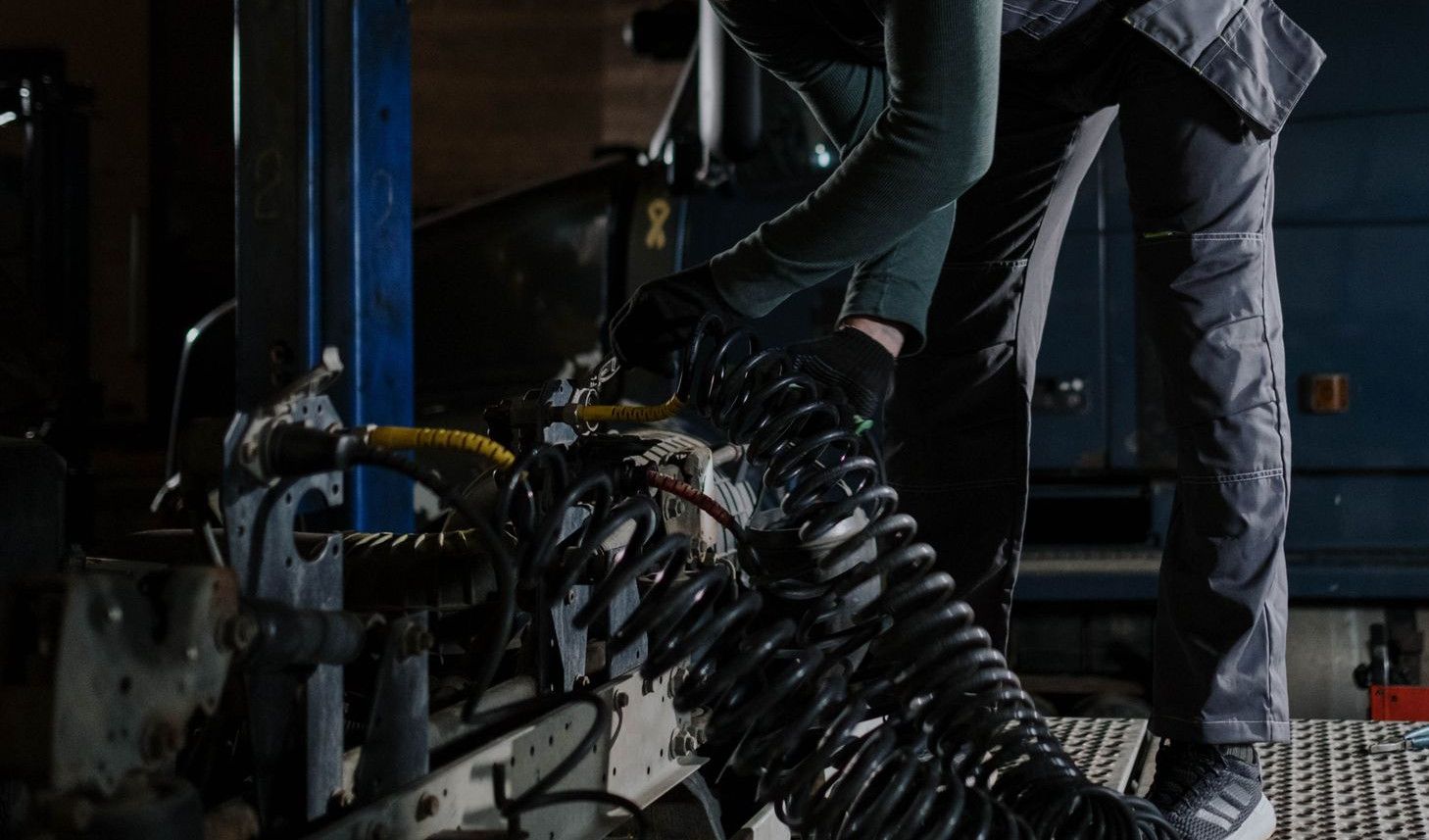 Mechanic fixing truck components indoors at an automotive repair shop.